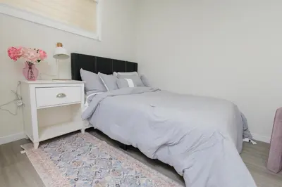 a white bedroom with a bed with a white nightstand at Cozy Quarters Your Comfy Haven in Calgary