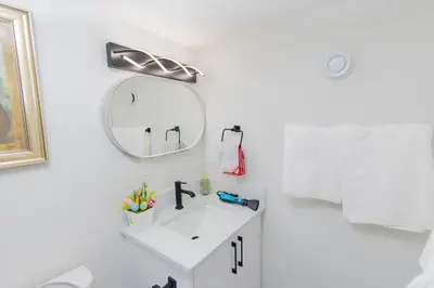 a white bathroom with a sink and a mirror at Cozy Quarters Your Comfy Haven in Calgary