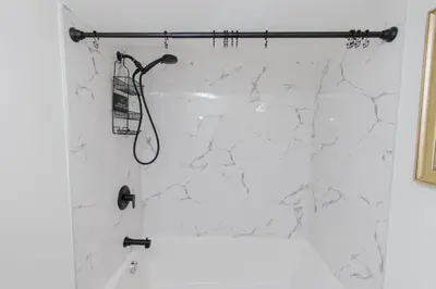 a shower with a white marble wall at Cozy Quarters Your Comfy Haven in Calgary