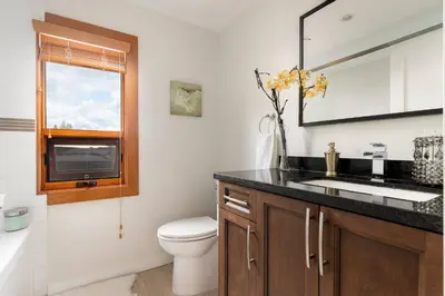 a bathroom with a sink and a toilet and a mirror at Quiet Modern Dundadrave Oasis in West Vancouver