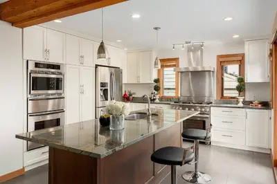 a kitchen with white cabinets and a large island at Quiet Modern Dundadrave Oasis in West Vancouver