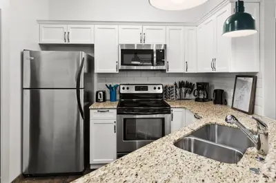 a kitchen with white cabinets and a stainless steel refrigerator at Chic Mountain View - Pool & HotTub - Fireplace - BBQ! in Canmore