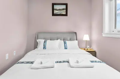 a white bedroom with a large bed with white pillows at Modern Private 3BR House in Vancouver