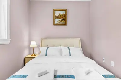 a bedroom with a white bed and a picture on the wall at Modern Private 3BR House in Vancouver