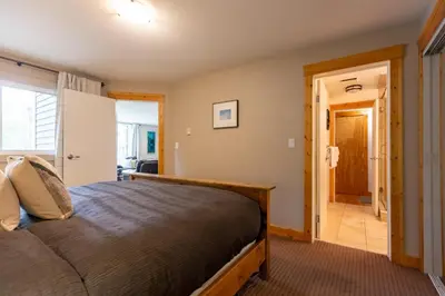 a bedroom with a bed and a hallway at Timberline - Spruce Lodge by Fernie Central Reservations in Fernie