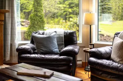 a leather couch sitting in a living room with a window at Timberline - Spruce Lodge by Fernie Central Reservations in Fernie