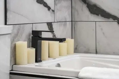a bathroom with a bath tub with candles on it at Nineteen55 4BR Parkside Home in Central Red Deer in Red Deer