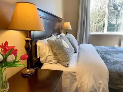 a bedroom with a bed with pillows and a table with a lamp at Urban Retreat in Nanaimo