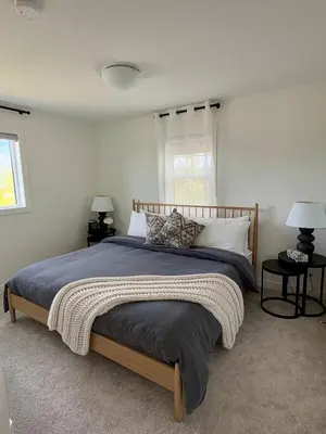 a bed in a bedroom with two lamps and a window at The Lamp House in Nordegg