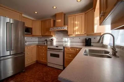 a kitchen with stainless steel appliances and wooden cabinets at Serene Garden Suite in Delta