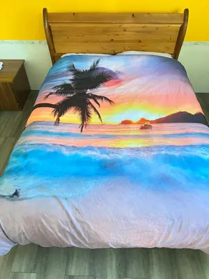 a bed with a painting of a palm tree on it at Surrey central in Surrey