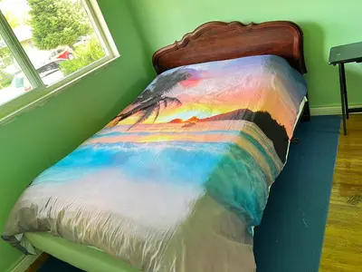 a bed with a colorful comforter with a window at surrey central green bamboo house in Surrey