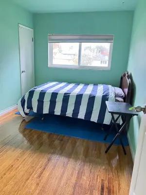 a bed in a room with a window and a table at surrey central green bamboo house in Surrey