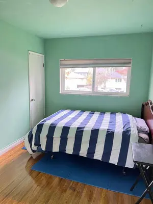 a bedroom with a bed with a striped comforter at surrey central green bamboo house in Surrey