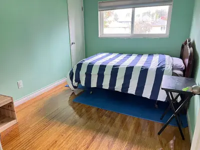 a bedroom with a bed and a wooden floor at surrey central green bamboo house in Surrey