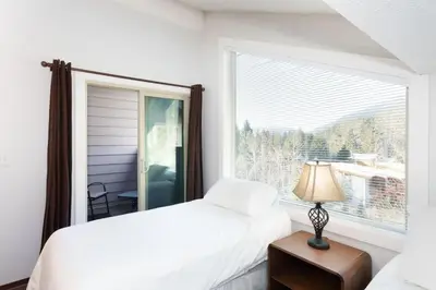 a bedroom with a white bed and a window at Whistler Corner Loft Next to lift with Amazing views! in Whistler