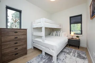 a bedroom with a white bunk bed and a dresser at Luxury Saratoga Beach Town Home in Oyster Bay