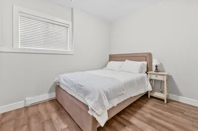 a white bedroom with a bed and a window at Nanaimo 2BR Oceanview Suite w/ Kitchen & Laundry in Nanaimo