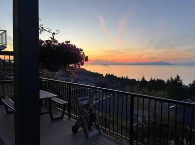 a balcony with a view of the ocean at sunset at Nanaimo 2BR Oceanview Suite w/ Kitchen & Laundry in Nanaimo