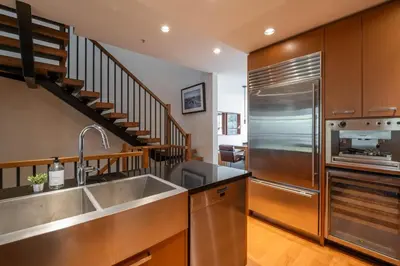 a kitchen with a sink and a stainless steel refrigerator at Fitzsimmons Walk 16 by Outpost Whistler in Whistler