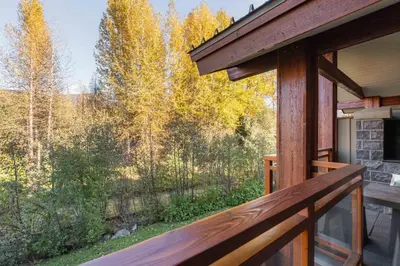 a deck with a view of the woods at Fitzsimmons Walk 16 by Outpost Whistler in Whistler
