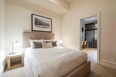 a white bedroom with a large white bed and a table at Fitzsimmons Walk 16 by Outpost Whistler in Whistler