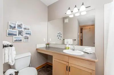 a bathroom with a sink and a toilet and a mirror at Evergreen Escape - 2 Bedroom Condo with Pool & Hot Tub in Canmore