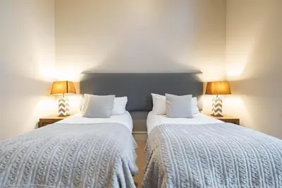 two beds in a room with two lamps on tables at Fitzsimmons Walk 26 by Outpost Whistler in Whistler