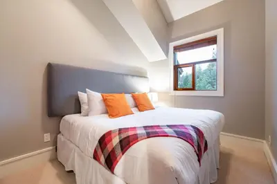 a bedroom with a bed with orange pillows and a window at Fitzsimmons Walk 26 by Outpost Whistler in Whistler
