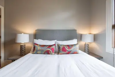 a white bed with two pillows and two lamps at Fitzsimmons Walk 35 by Outpost Whistler in Whistler