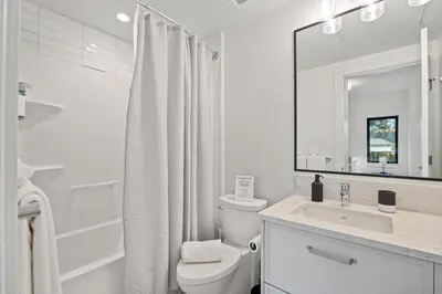 a white bathroom with a toilet and a sink at Family-Friendly Beachside Bliss in Oyster Bay