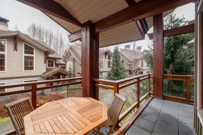 a patio with a wooden table and chairs on a balcony at Fitzsimmons Walk 37 by Outpost Whistler in Whistler