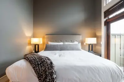 a bedroom with a large white bed with two lamps at Fitzsimmons Walk 37 by Outpost Whistler in Whistler