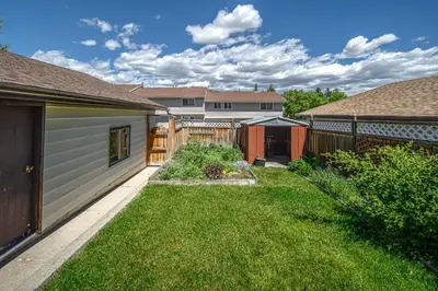 a backyard with a fence and a yard with green grass at Centrally located 1 Bed 1 Bath Ensuite Cute Guest Suite Private Laundry Pet OK in Calgary