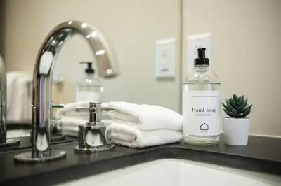 a bathroom sink with a bottle of hand soap and towels at Fitzsimmons Walk 38 by Outpost Whistler in Whistler