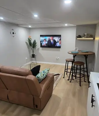 a living room with a couch and a tv on a wall at Cozy 2 bedroom basement with side entrance in Bélanger
