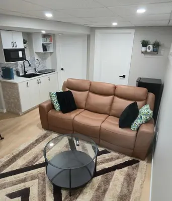 a living room with a brown couch and a glass table at Cozy 2 bedroom basement with side entrance in Bélanger