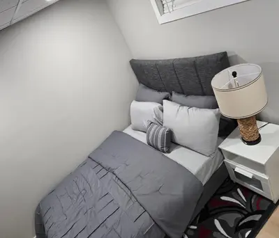 a bedroom with a bed with a lamp and pillows at Cozy 2 bedroom basement with side entrance in Bélanger