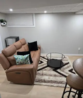 a living room with a brown couch and a table at Cozy 2 bedroom basement with side entrance in Bélanger