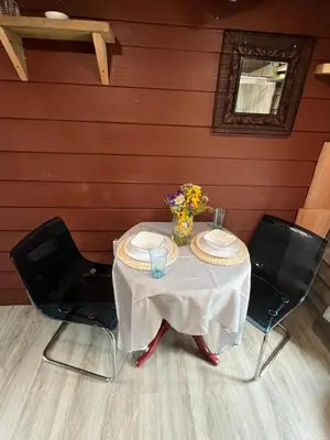 a table with two chairs and a vase of flowers on it at Rustic Guesthouse in Sayward