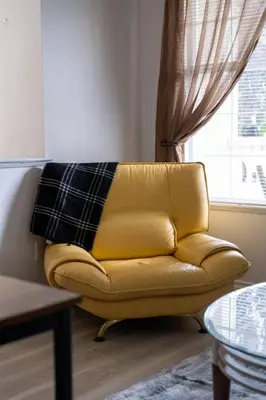 a yellow leather couch in a living room with a window at 3BR 2BA Surrey Home | Quiet & Convenient in Surrey