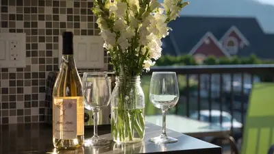 a table with two glasses and a bottle of wine and flowers at Klippers Guest Suites in Cawston