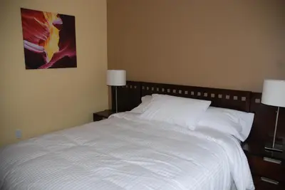 a bedroom with a bed with white sheets and two lamps at Klippers Guest Suites in Cawston