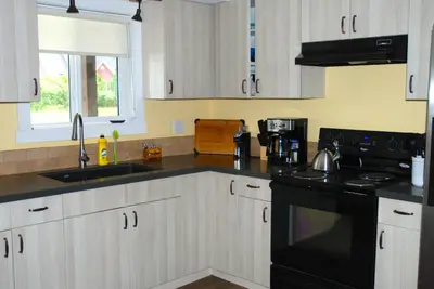 a kitchen with white cabinets and a black stove top oven at Klippers Guest Suites in Cawston