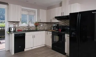 a kitchen with white cabinets and a black refrigerator at Klippers Guest Suites in Cawston
