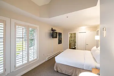 a white bedroom with a bed and a window at Glacier Lodge 309 by Outpost Whistler in Whistler