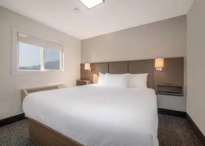 a large white bed in a room with a window at Coast Penticton Hotel in Penticton