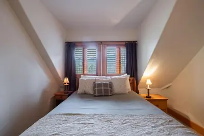 a bedroom with a bed with two lamps and a window at Heron Chalet by Outpost Whistler in Whistler