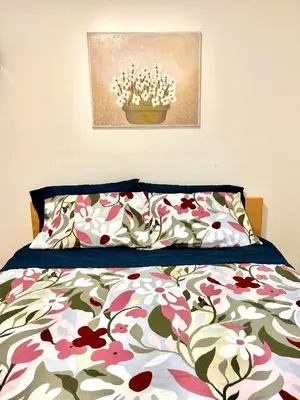 a bedroom with a bed with a floral bedspread at Private Entire Guest Suite, 1 min to bus stops to Downtown and major attractions in Vancouver