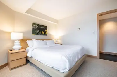 a bedroom with a large white bed and a lamp at Le Chamois 508 by Outpost Whistler in Whistler